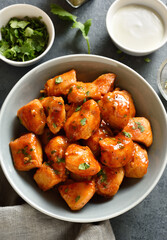 Delicious chicken bites in sauce in bowl over dark background