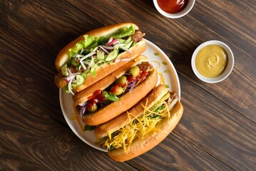 Hot dogs loaded with assorted toppings on wooden background