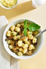 Potato gnocchi with mushrooms, cheese and greens in bowl