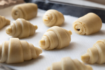 Close up of uncooked fluffy leavened traditional French croissants dough in a baking tray. It's a buttery, flaky pastry fold with butter in multiple layers, origin from Austrian.