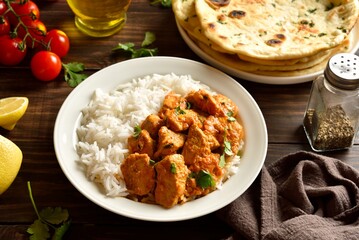 Butter chicken with basmati rice on plate on wooden table