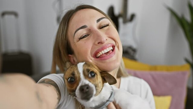 A joyful woman takes a selfie with her affectionate dog at home.