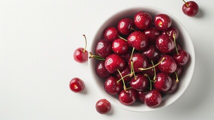 A bowl of cherries is sitting on a white table