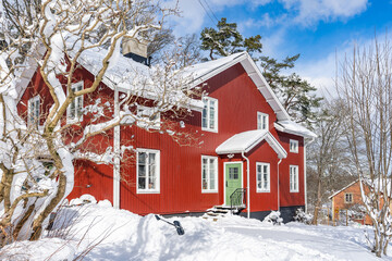 Traditional old big red wooden house in winter countryside. Beautiful Swedish cottage or villa . Christmas landscape in northern Europe. Snowy village.
