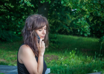Girl talking on the phone on a bench in a cozy park