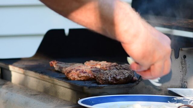 Authentic back yard grilling burgers and stake, flames smoke, good summer time, selective focus real time video. 