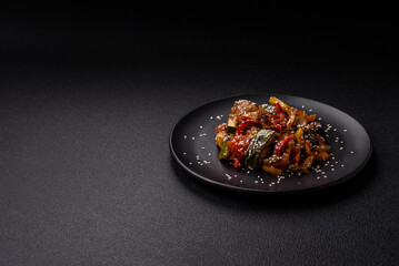 Spicy Asian dish with sliced meat fillet, hot pepper, carrots and sesame seeds