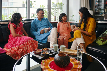 Indian family of four sitting together at home and talking to each other