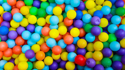A colorful sea of bouncy balls in the kids' playground. A collection of brightly colored balls pit, mostly in shades of blue, yellow, red, and purple, fill the frame.