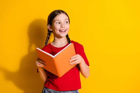 Photo of lovely small girl book look empty space wear t-shirt isolated on yellow color background