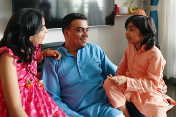 Happy dad talking to his children during his leisure time at home