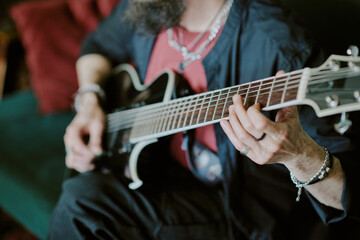 Obraz premium High angle view closeup of hands of unrecognizable bearded rock musician playing guitar