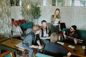 High angle shot of group of male and female rock musicians spending time together in their studio in abandoned house working on new album