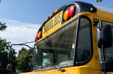 Shot of retro-styled yellow school bus with extended red stop sign standing still on serene road, empty vehicle with no driver awaiting children to boarding, transportation concept, copy space