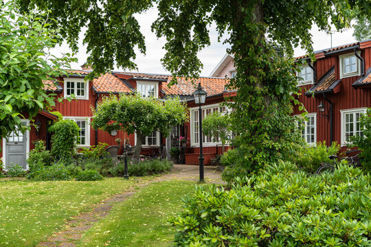 Old wooden red houses of past centuries in Sigtuna, ancient capital of Sweden. Two storey houses with beautiful garden design. Courtyard with lanterns. 