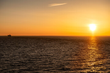Baltic sea at sunset. Clear sky with glowing golden sun, reflections in the water. Setting sun. Epic seascape. Abstract natural pattern, texture, background, concept image
