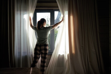 Obraz premium Woman Drawing Curtains Open in Morning Light