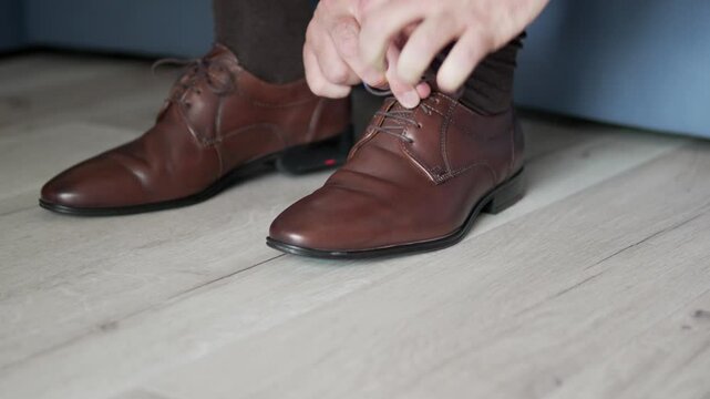 Capture the stylish moment of a male getting ready, showcasing elegant brown shoes as part of his preparation for a special occasion or event.