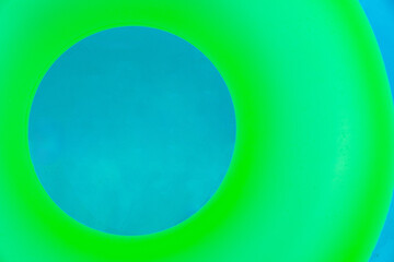 Bright vivid green children inflatable ring in swimming pool, top view. Shot for design. Summer vacation concept. Hotel spa resort advertisement. Beach and water toys