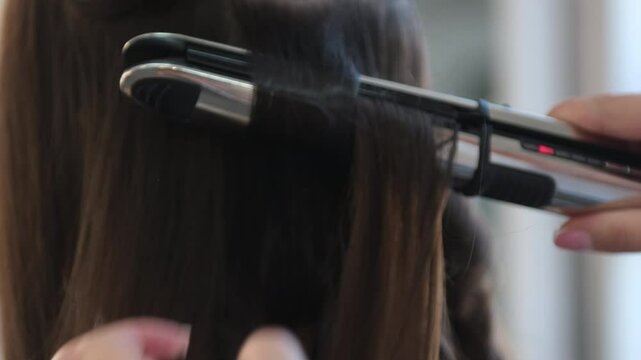 stylist hairdresser making hairstyle using curling tongs for long hair of unrecognizable woman in beauty salon. Concept of beauty and fashion. Hairdresser makes hairstyle.Curling Hair