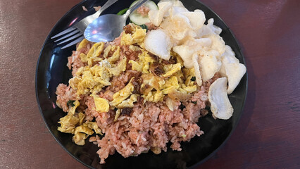 Nasi goreng jawa or javanese fried rice chicken with vegetable and crackers on white plate. Indonesian food Asian cuisine. Nasi Goreng is an Indonesian cuisine dish with jasmine rice, chicken meat