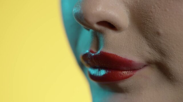woman licking her lips, red lipstick, yellow background