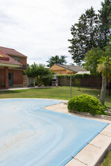 Summer pool covered with a blue tarp to protect the water from dirt in the off-season. End or beginning of season, fall or spring