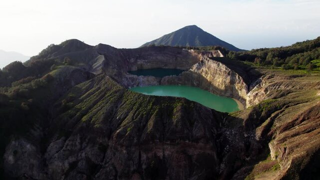 A breathtaking drone shot of Kelimutu Volcano in Indonesia, highlighting its vibrant crater lakes and rugged terrain
