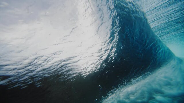 Sideview underwater angle behind tropical blue ocean wave crashing on reef shimmering