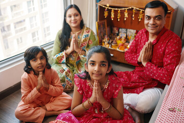 Portrait of Indian family smiling at camera while praying near the altar at home
