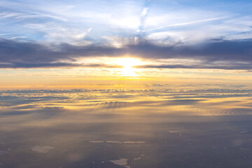 Aerial view of spectacular orange sunset above thin layer of clouds