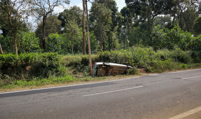 An Accident scene where a Sedan car has overturned and fallen into a road side ditch in the forest...