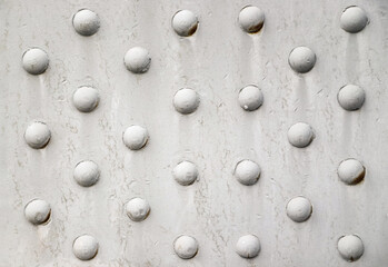 Riveted with button-head rivets metal plate painted in white as an industrial background