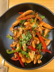 Fajitas Chicken meat, sliced bell pepper, and parsley in a frying pan.