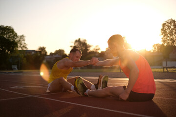Two track and field athletes doing stretching on the stadium field before running