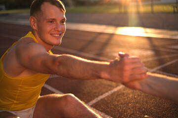 Obraz premium Two track and field athletes doing stretching on the stadium field before running