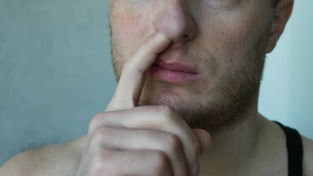 Pick your nose with your finger. The man stuck his finger into the nostril of his nose.