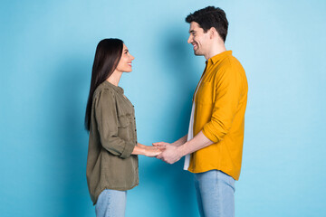 Profile photo of two nice young partners hold arms wear shirt isolated on blue color background