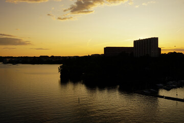 Naklejka premium Silhouette buildings by river against sky during sunset