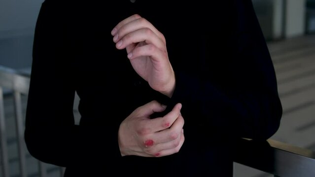 boxer with broken hands bleeding puts on a black shirt. Handsome man with black hair and blue eyes. Mixed race nationality. Close up boxing trainer or manager wrapping hands of a boxer reparing
