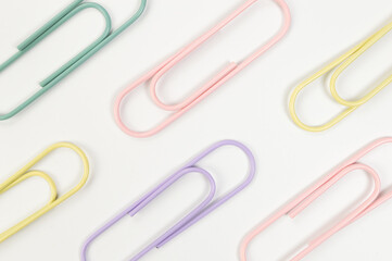 Top view of colorful paperclips on white background. School, office wallpaper. Flat lay, copy space.