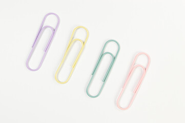 Top view of colorful paperclips on white background. School, office wallpaper. Flat lay, copy space.