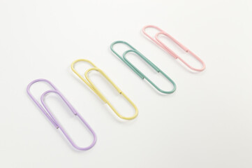 Top view of colorful paperclips on white background. School, office wallpaper. Flat lay, copy space.