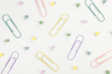 Top view of paperclips and pins on white background. School, office wallpaper. Flat lay, copy space.