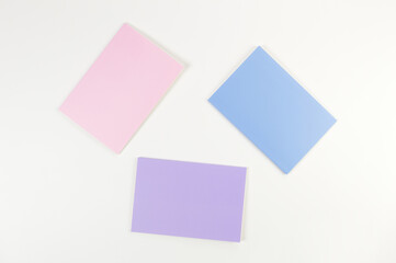 Top view of pink, purple and blue notebooks on white background. School, office wallpaper. Flat lay, copy space.