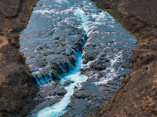 Majestic summer aerial view of Bruarfoss Waterfall. The Icelands Bluest Waterfall. Blue water flows...
