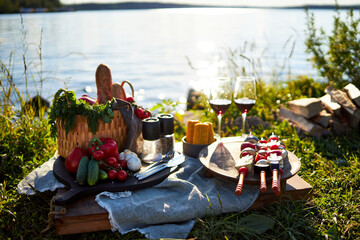 Background on a tray on the river bank in summer on a picnic with vegetables, kebab and glasses of red wine