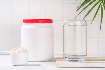 Collagen protein powder with glass of water on white kitchen table. Natural supplement for beauty, health of skin, bones, joints and intestines, anti-age concept