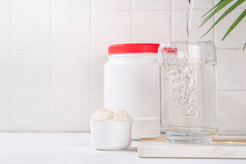 Collagen protein powder with glass of water on white kitchen table. Natural supplement for beauty, health of skin, bones, joints and intestines, anti-age concept