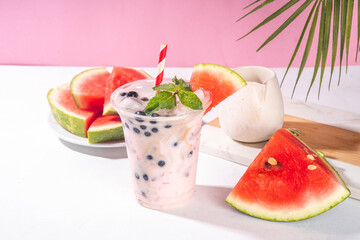 Watermelon boba balls bubble tea cocktail. Refreshing milky non-dairy milkshake cocktail with boba balls and watermelon slices on background. Summer garnished sweet dessert iced drink 